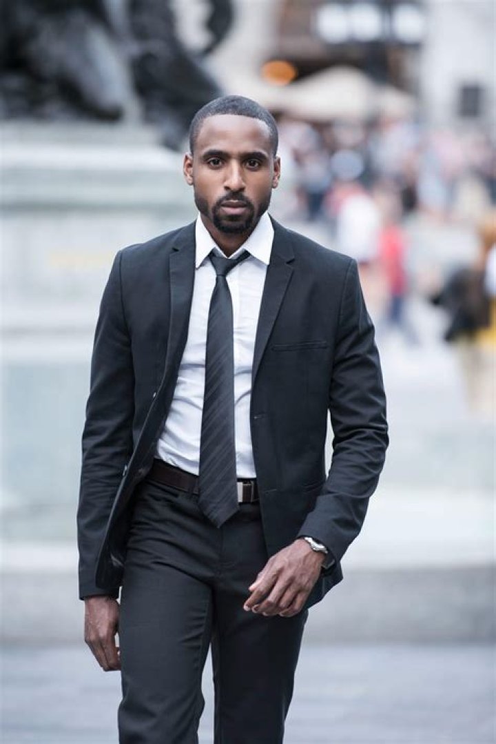 a man wearing a black t shirt looking off into the distance with his